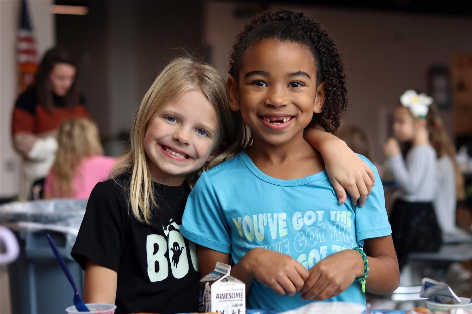 2 girls smiling in the Aspen Grove Elementary lunchroom